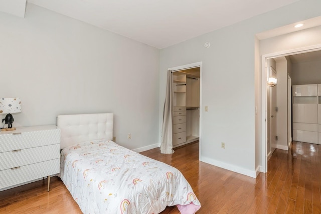 bedroom featuring a walk in closet and wood-type flooring