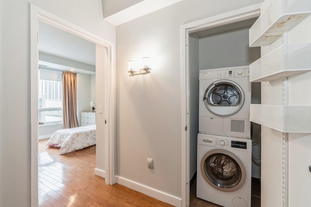 clothes washing area with stacked washing maching and dryer and light hardwood / wood-style floors