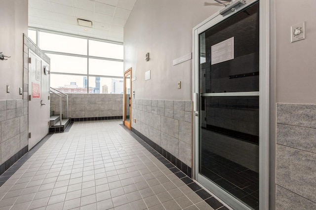 interior space featuring expansive windows, tile walls, and dark tile patterned floors