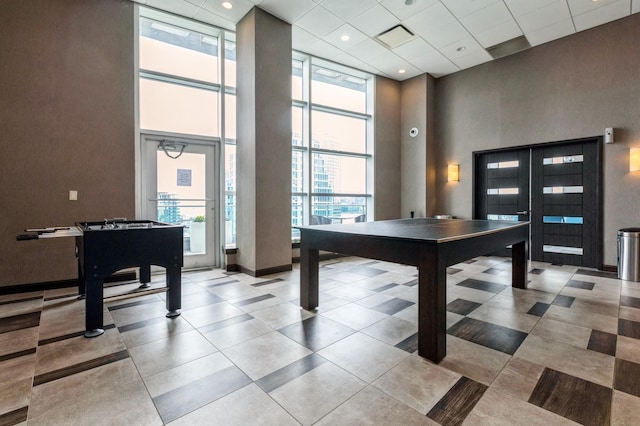 recreation room with floor to ceiling windows and a high ceiling