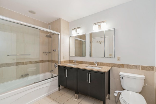 full bathroom with toilet, bath / shower combo with glass door, tile walls, vanity, and tile patterned flooring