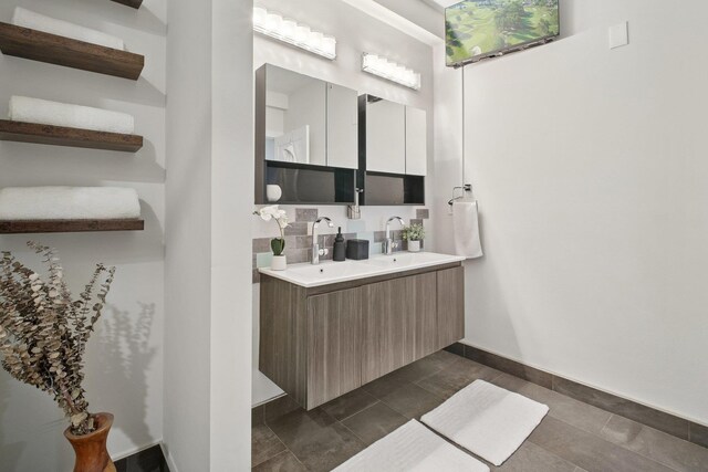 full bath with a sink, baseboards, tile patterned floors, and double vanity