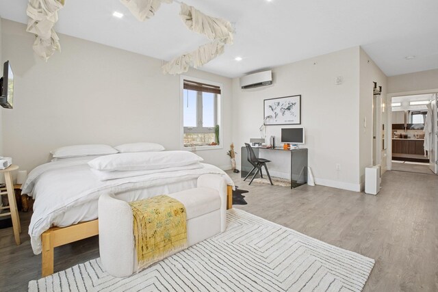bedroom featuring an AC wall unit, recessed lighting, baseboards, and wood finished floors