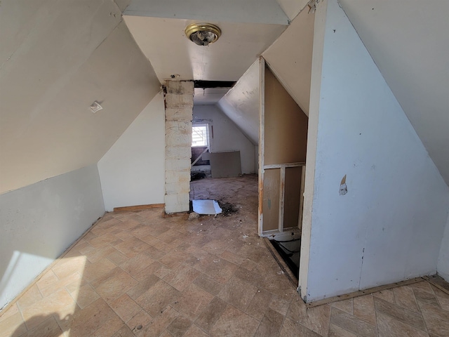 bonus room with stone finish flooring and lofted ceiling