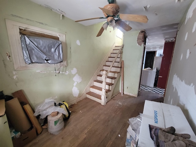 unfurnished living room with ceiling fan, wood finished floors, and stairway