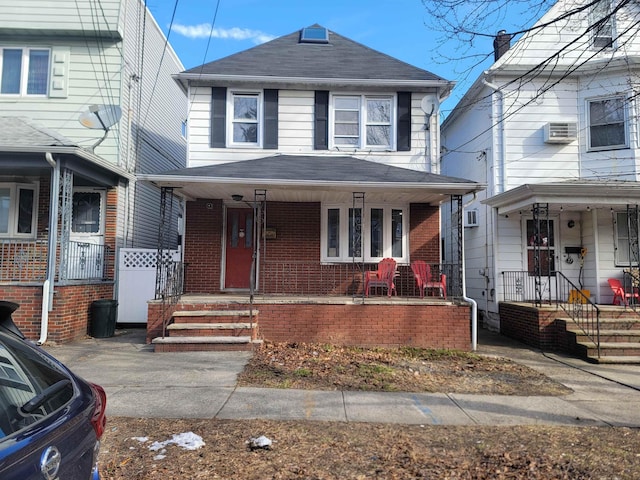 american foursquare style home featuring brick siding, a shingled roof, and covered porch