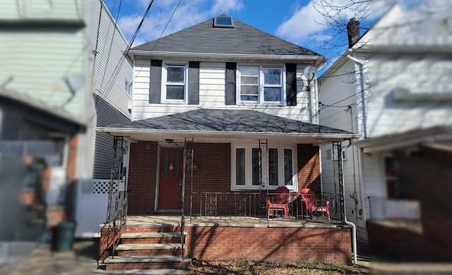 american foursquare style home with covered porch, brick siding, and roof with shingles