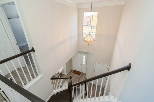 stairway with hardwood / wood-style flooring, a chandelier, and ornamental molding