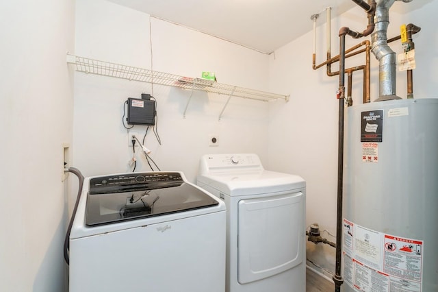 washroom with washing machine and clothes dryer, gas water heater, and hardwood / wood-style floors