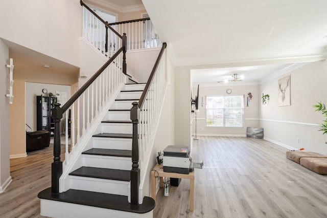 staircase with hardwood / wood-style flooring and crown molding