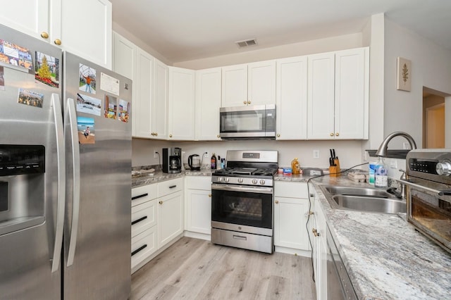 kitchen featuring light hardwood / wood-style flooring, light stone countertops, white cabinets, and stainless steel appliances