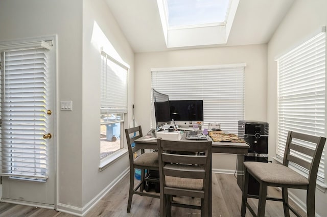 office area with vaulted ceiling with skylight and light wood-type flooring