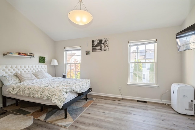 bedroom with light wood-type flooring and vaulted ceiling