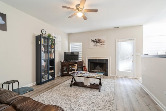 living room featuring a fireplace, ceiling fan, and light hardwood / wood-style flooring