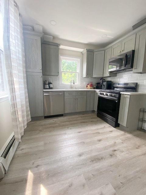 6 Stone Ave, Elmwood Park, NJ 07407 - kitchen with stainless steel appliances, baseboard heating, light wood-style floors, gray cabinetry, and tasteful backsplash