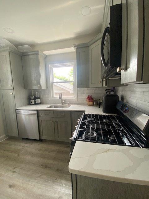 6 Stone Ave, Elmwood Park, NJ 07407 - kitchen featuring black appliances, backsplash, light wood-type flooring, and light stone countertops
