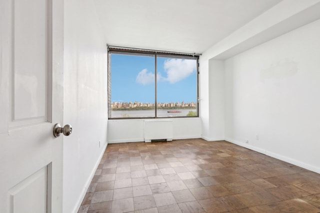 unfurnished room with radiator heating unit and baseboards