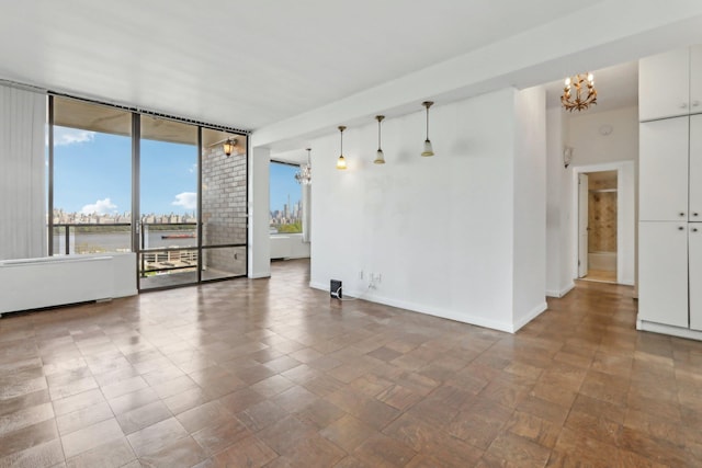empty room featuring an inviting chandelier, baseboards, and a water view
