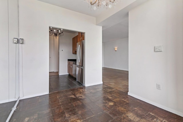 empty room featuring baseboards and a chandelier