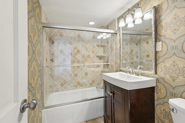 bathroom with toilet, enclosed tub / shower combo, and vanity