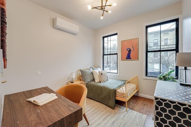 bedroom featuring light wood-type flooring, a chandelier, multiple windows, and a wall unit AC