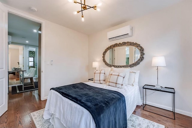 bedroom featuring a wall unit AC, an inviting chandelier, and hardwood / wood-style floors