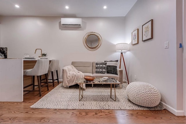 sitting room with hardwood / wood-style flooring and a wall mounted air conditioner