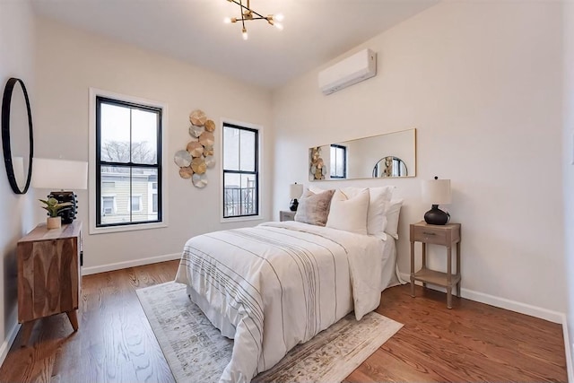 bedroom with an inviting chandelier, hardwood / wood-style flooring, and an AC wall unit