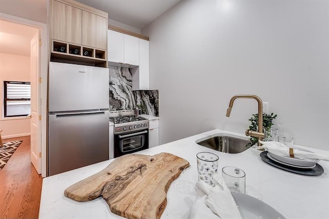 kitchen with stainless steel appliances, sink, and light hardwood / wood-style flooring