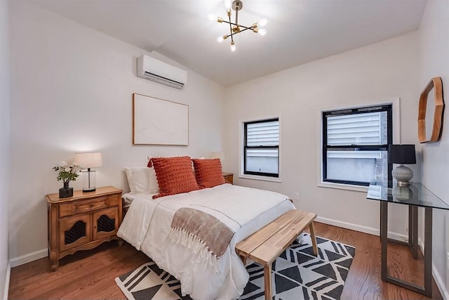 bedroom featuring dark hardwood / wood-style flooring, an inviting chandelier, and an AC wall unit