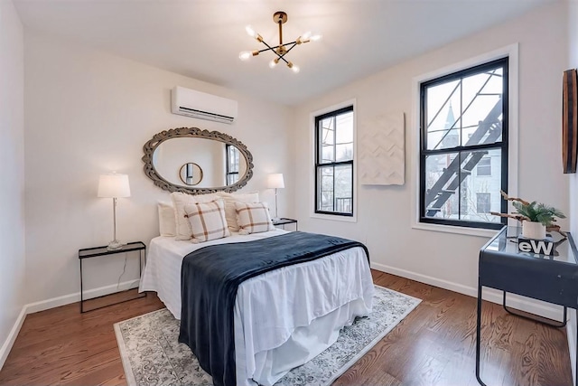 bedroom featuring dark hardwood / wood-style flooring, a wall mounted air conditioner, and an inviting chandelier