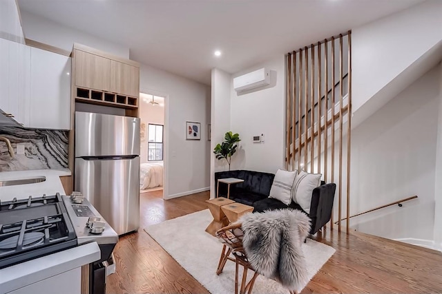 kitchen featuring stainless steel appliances, sink, light wood-type flooring, backsplash, and a wall mounted air conditioner