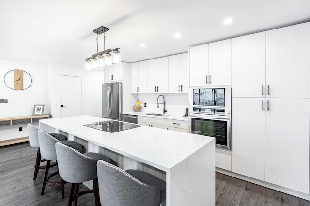 kitchen featuring sink, a kitchen island, stainless steel appliances, and decorative light fixtures