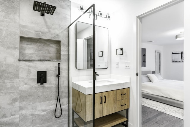 bathroom featuring tiled shower, wood-type flooring, and vanity