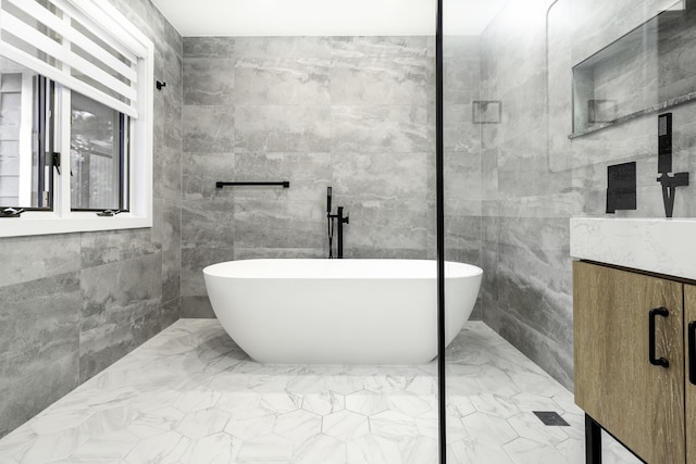 bathroom with a bathtub, tile walls, and vanity