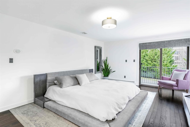 bedroom featuring baseboard heating, access to exterior, and hardwood / wood-style flooring