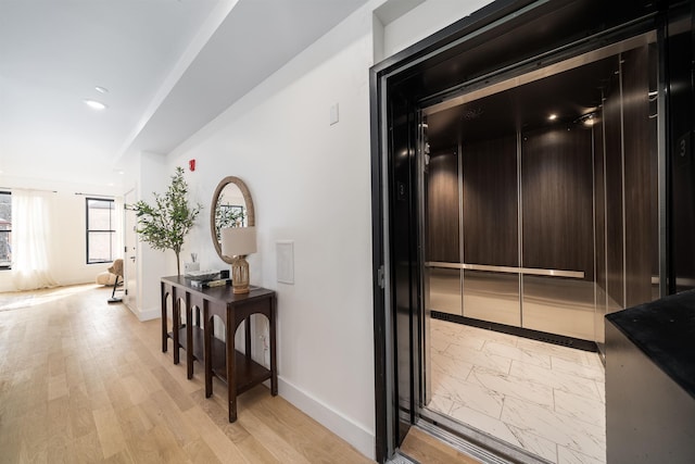 hall featuring elevator, recessed lighting, baseboards, and light wood-style floors