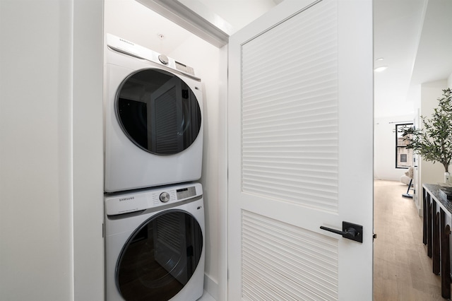 laundry area with laundry area, stacked washing maching and dryer, and light wood-style floors