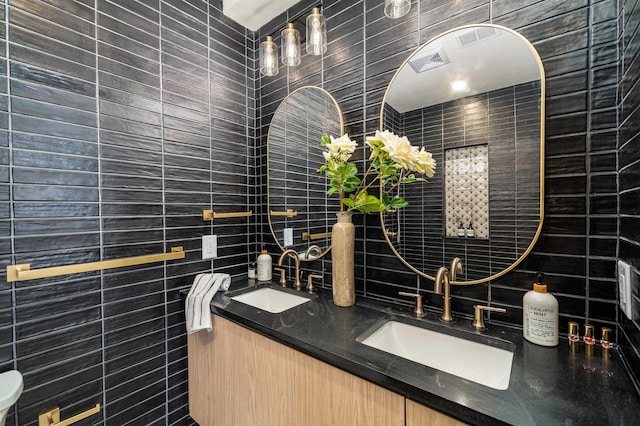 full bath with double vanity, tile walls, and a sink