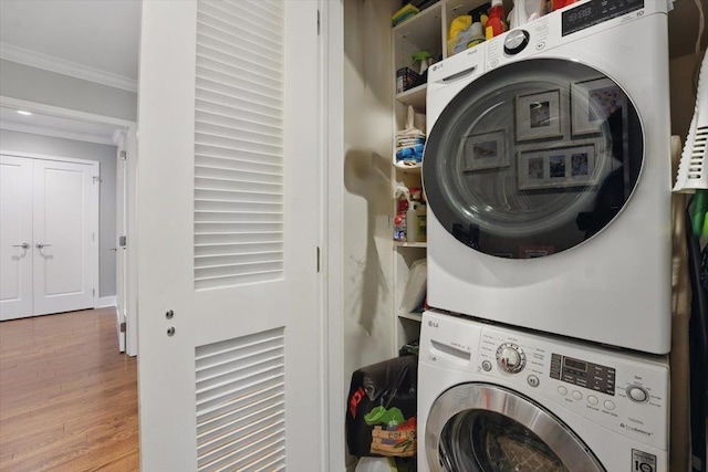 laundry area featuring stacked washer / dryer, crown molding, and wood finished floors