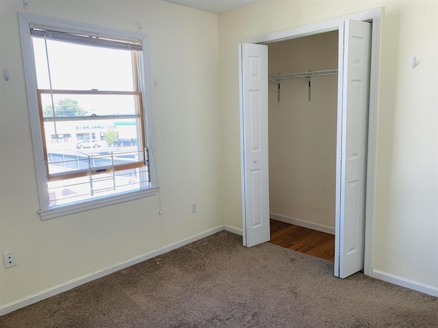 unfurnished bedroom featuring a closet, multiple windows, baseboards, and carpet floors