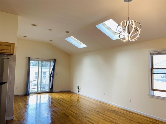 unfurnished living room with lofted ceiling with skylight, a healthy amount of sunlight, and wood finished floors