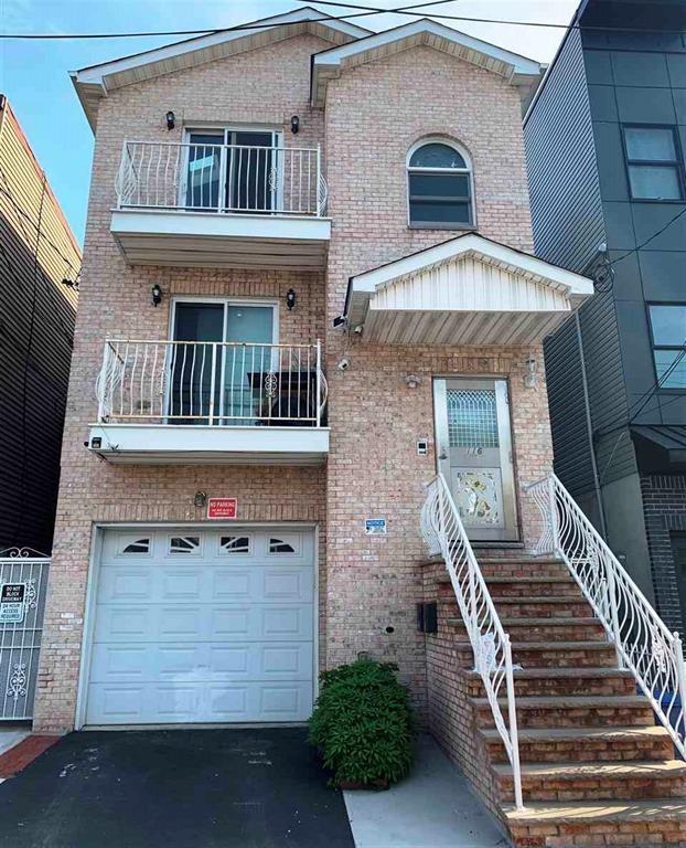 view of front facade featuring brick siding, a balcony, driveway, and a garage