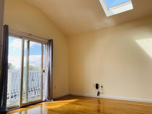 interior space featuring baseboards, vaulted ceiling with skylight, and wood finished floors