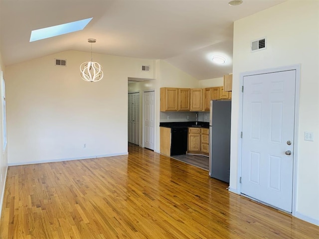 kitchen with visible vents, black dishwasher, dark countertops, and freestanding refrigerator