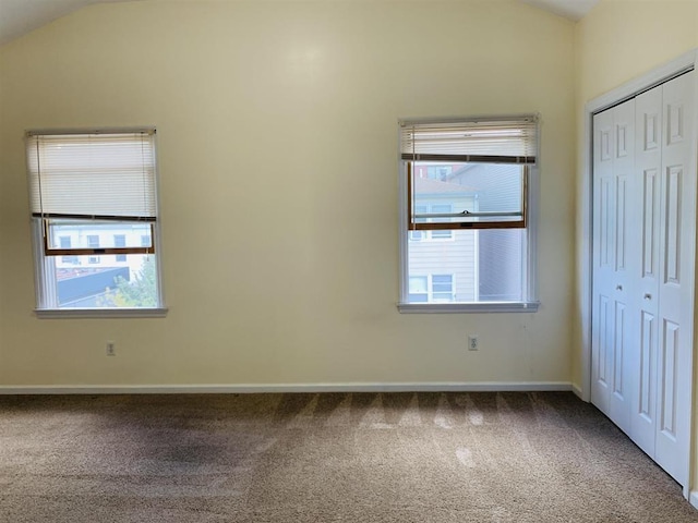 unfurnished bedroom with multiple windows, lofted ceiling, carpet, and a closet