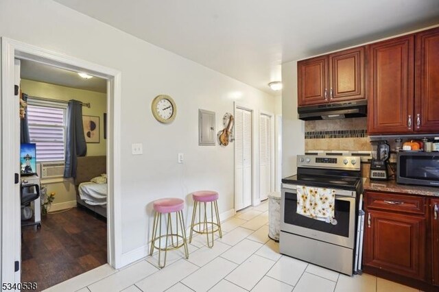 kitchen featuring decorative backsplash, stainless steel appliances, dark brown cabinets, under cabinet range hood, and light tile patterned flooring