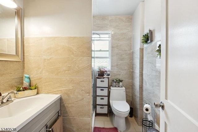 bathroom featuring toilet, vanity, tile walls, and tile patterned floors