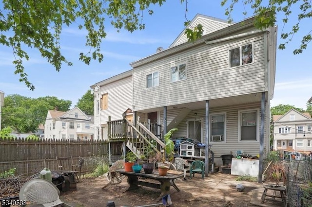 rear view of property featuring fence, a patio, and stairs