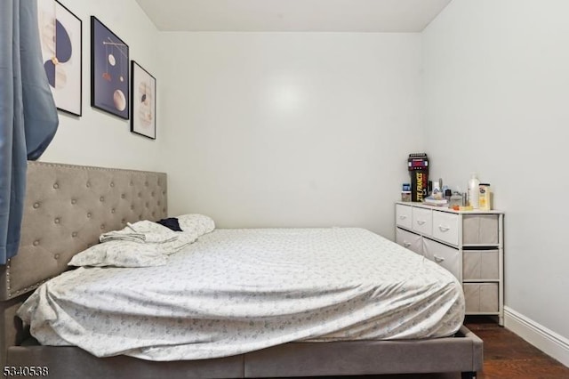 bedroom with baseboards and dark wood-type flooring